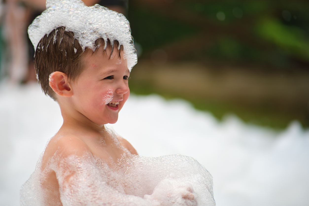 A small child covered in foam, having fun at a foam birthday party in Central Illinois