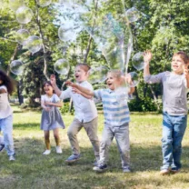 A group of children getting excited by big bubbles being blown at a bubble party from Mike's Trackless Trains