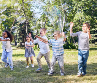 A group of children getting excited by big bubbles being blown at a bubble party from Mike's Trackless Trains