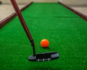 Hitting a ball on a portable mini golf rental course, provided by Mike's Trackless Trains in Central Illinois