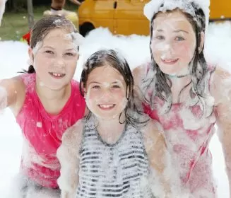 Three young girls covered in foam and enjoying their foam party, one of the Party & Event Rentals offered by Mike's Trackless Trains